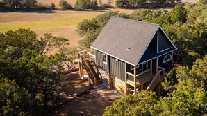 A cabin with a steep roof, wooden deck, and a small staircase leading to a porch.