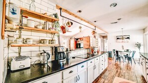 A kitchen with white cabinets, a black countertop, and wooden shelves.