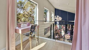 A modern apartment with a balcony, a desk, and a chair. - Treetop House: King Loft & Outdoor Soaking Tub | Wimberley Hill Country (Wimberley)
