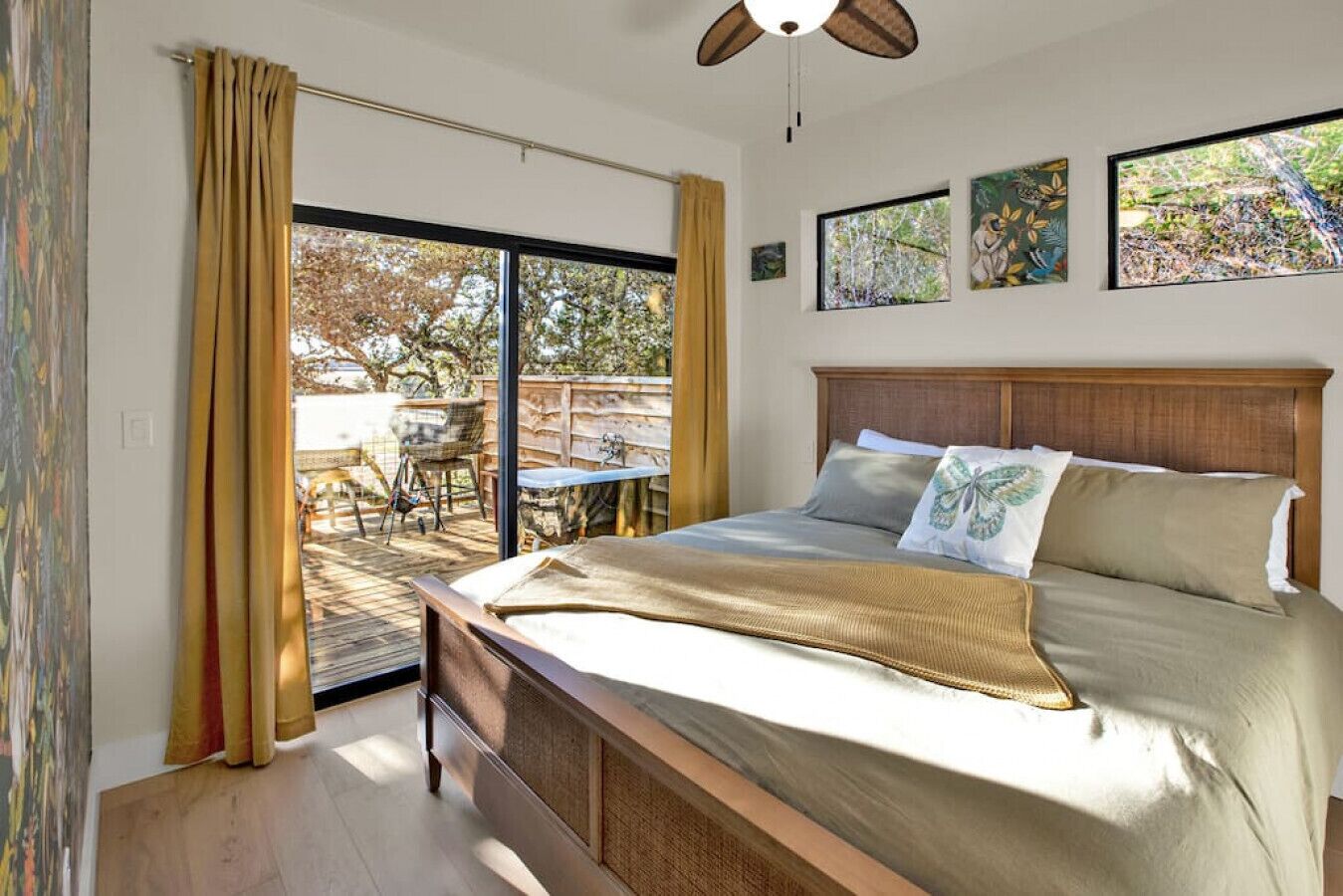 A bedroom with a bed, a ceiling fan, and a sliding glass door leading to an outdoor area.