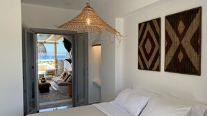 A bedroom with a bed, a hanging rattan light fixture, and two wall-mounted decorative panels. - Beachhouse Omega Naxos - luxury holiday house - private pool & stunning sea view (Naxos)