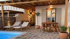 A poolside area with lounge chairs, a wooden table, and potted plants. - Beachhouse Omega Naxos - luxury holiday house - private pool & stunning sea view (Naxos)