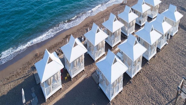 Una propiedad frente a la playa con varias cabañas blancas alineadas a lo largo de la orilla.