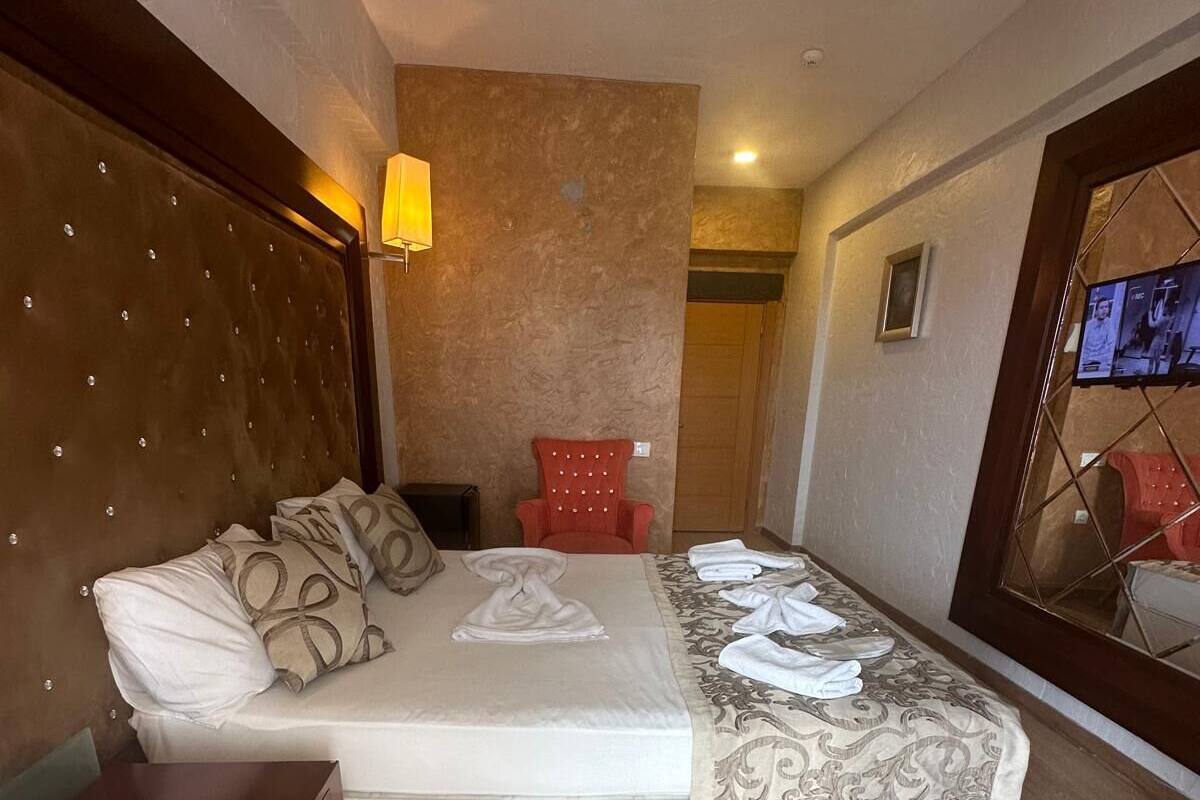 A hotel room with a large bed, a wooden headboard, a small desk with a telephone, and a red chair.