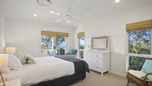 Une chambre à coucher avec un lit, une commode, une chaise et un ventilateur de plafond.