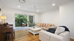 Un salon moderne avec un piano, un canap é, une table basse et un ventilateur de plafond.