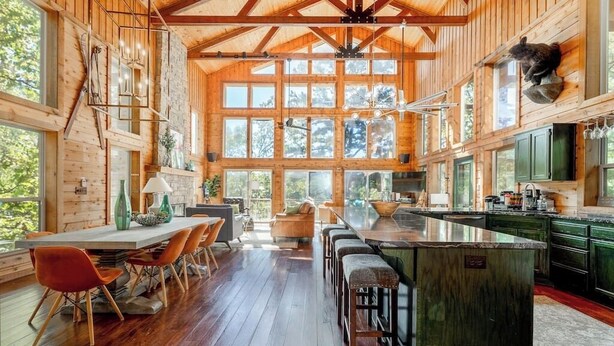 Una cocina amplia con una isla grande, pisos de madera y un techo alto con vigas a la vista.