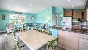 A spacious living area with a dining table, a sofa, and a kitchen with wooden cabinets and a granite countertop. - Private pool home with dockage 3/2 near Sombrero (Marathon)