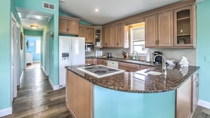 A kitchen with wooden cabinets, granite countertops, and a central island. - Private pool home with dockage 3/2 near Sombrero (Marathon)