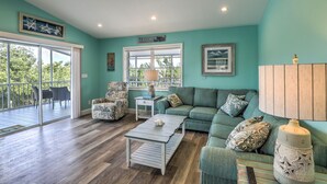 A spacious living room with teal walls, a large window, a sofa, a coffee table, and a chair. - Private pool home with dockage 3/2 near Sombrero (Marathon)