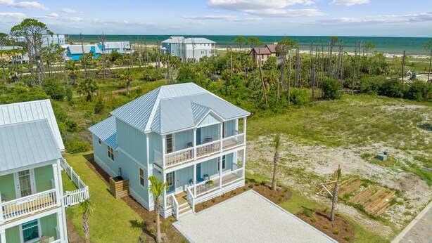 A coastal property with a two-story house featuring a balcony, a fenced yard, and a view of the ocean. - Super Cute House on the Cape - Walk to Beach - Dog Friendly! (Port St Joe)