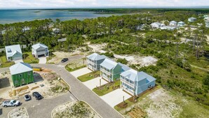 A coastal residential area with multiple houses, a paved road, and a view of the ocean. - Super Cute House on the Cape - Walk to Beach - Dog Friendly! (Port St Joe)