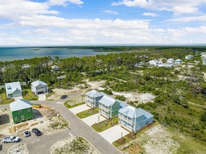 A coastal residential area with multiple houses, a paved road, and a view of the ocean.
