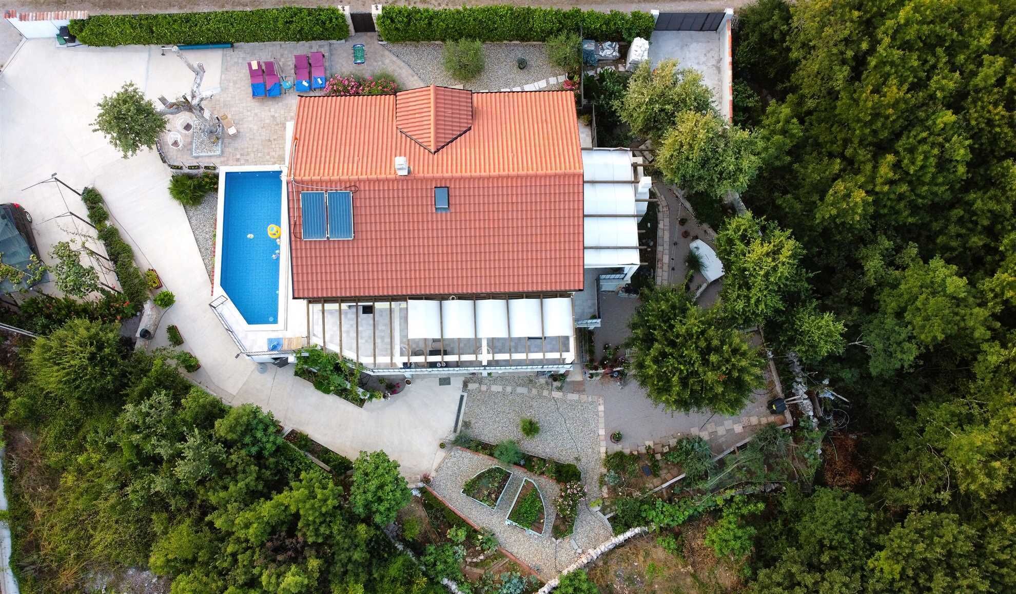 Ein Gebäude mit rotem Dach, Schwimmbad und Garten.