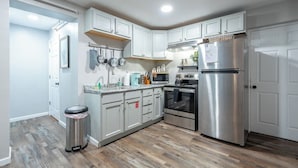 A modern kitchen with white cabinets, stainless steel appliances, and a wooden floor. - Suite 118 - Harmony at Rock Spring Resort (Rock Spring)