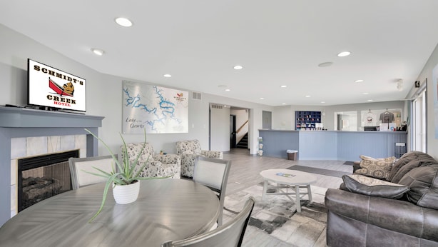 A modern hotel lobby with a fireplace, a dining area with a round table, patterned sofas, and a reception desk. - Schmidt's Creek Hotel (Osage Beach)