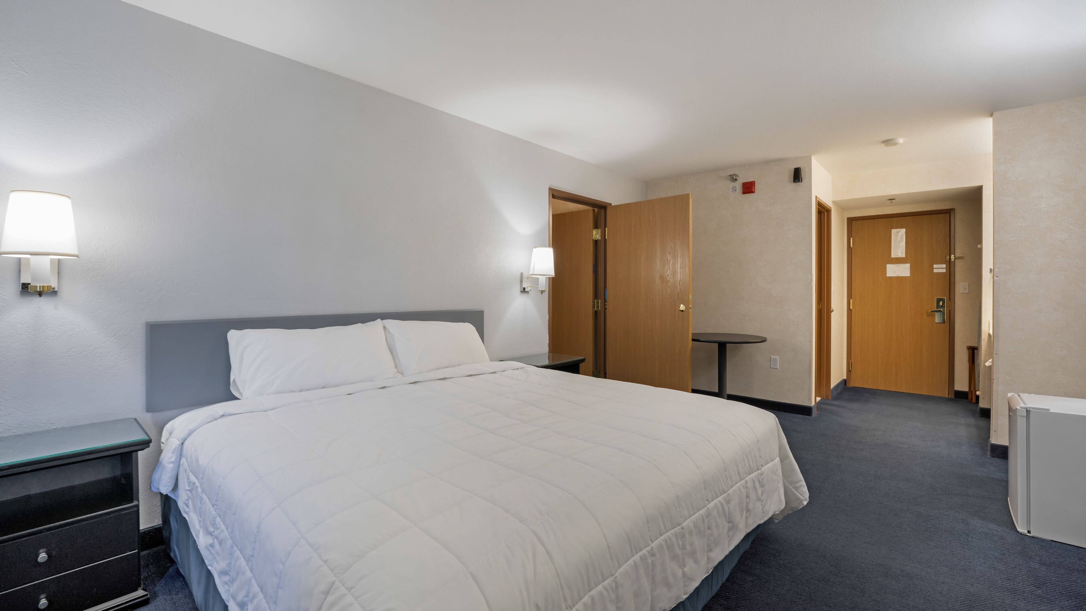 A hotel room with a large bed, bedside tables, a desk, and a chair.