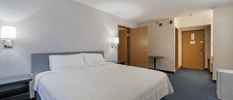 A hotel room with a large bed, bedside tables, a desk, and a chair.