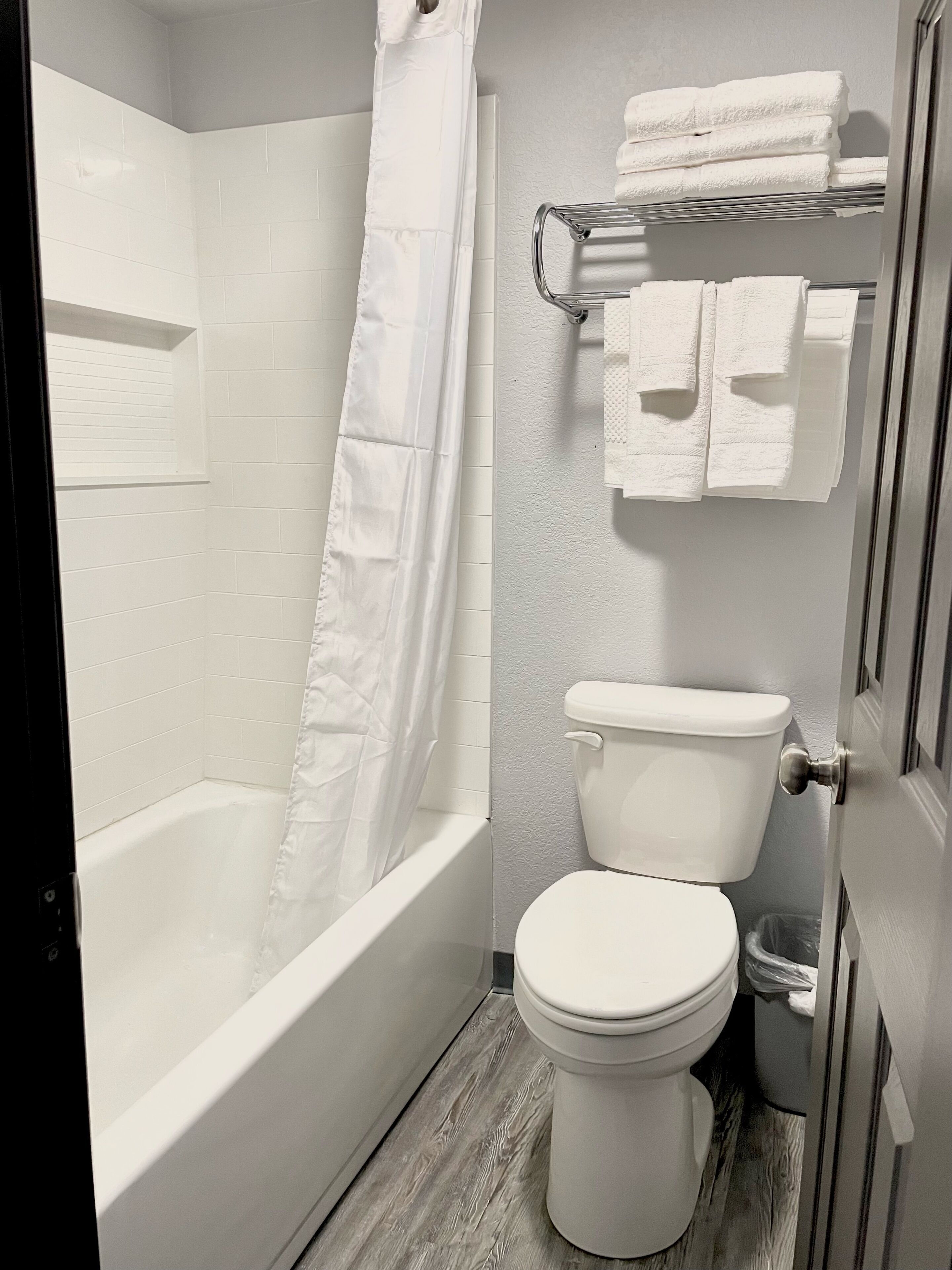 A modern bathroom with a white bathtub, toilet, and shower curtain.