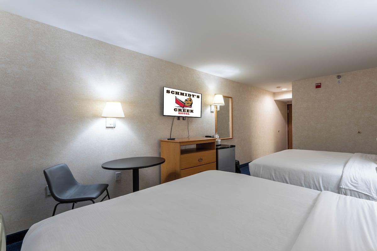 Une chambre d’hôtel avec deux lits, un bureau, une chaise et une petite table.