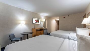 A hotel room with two beds, a desk, a chair, and a small table.
