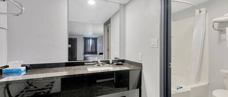 Un baño moderno con lavamanos de superficie negra, un espejo y cabina de ducha.