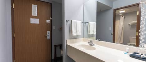 Une salle de bain avec une porte en bois, un lavabo avec un miroir et un porte-serviettes.
