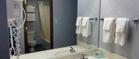 A bathroom with a double sink, a mirror, a hairdryer, and towels on a rack.