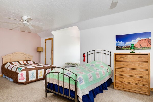 A bedroom with a bed, a dresser, a ceiling fan, and a painting on the wall. - Hacienda Roja - The Cedars #7 at Wind Walker Homestead (Spring City)