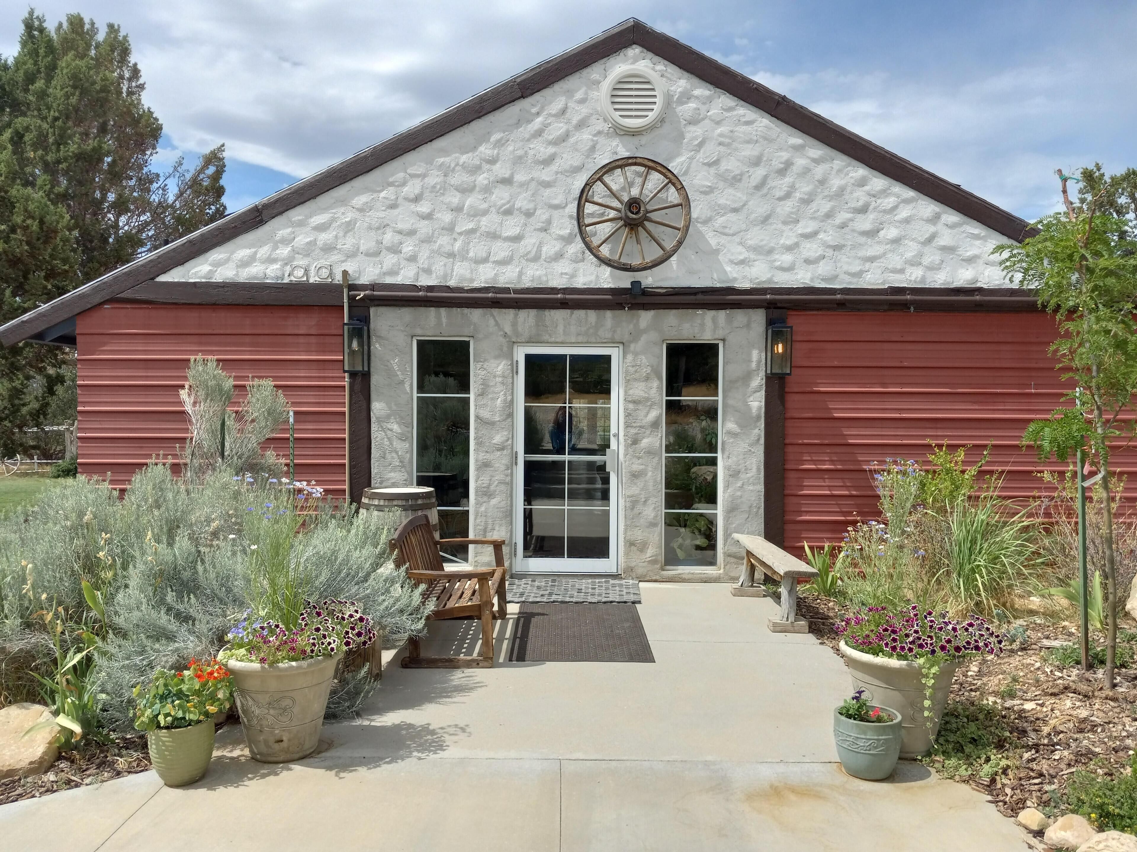 A rustic building with a white exterior, a wooden wheel feature on the roof, and a red exterior wall.