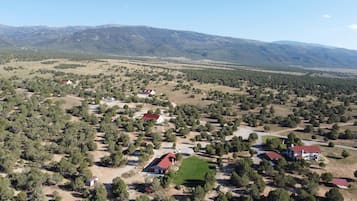 Vista aérea de una zona rural con casas dispersas, campos verdes y una cadena montañosa al fondo.