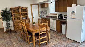 A kitchen with wooden cabinets, a white refrigerator, a dishwasher, and a dining table with chairs.