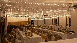 A banquet hall with tables set for a formal event, decorated with string lights and white tablecloths. - Hacienda Roja - The Juniper #5 at Wind Walker Homestead (Spring City)