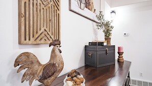 A wooden dining table with a decorative rooster, a framed picture, and a small plant on the wall above. - Hacienda Roja - The Sage #6 at Wind Walker Homestead (Spring City)