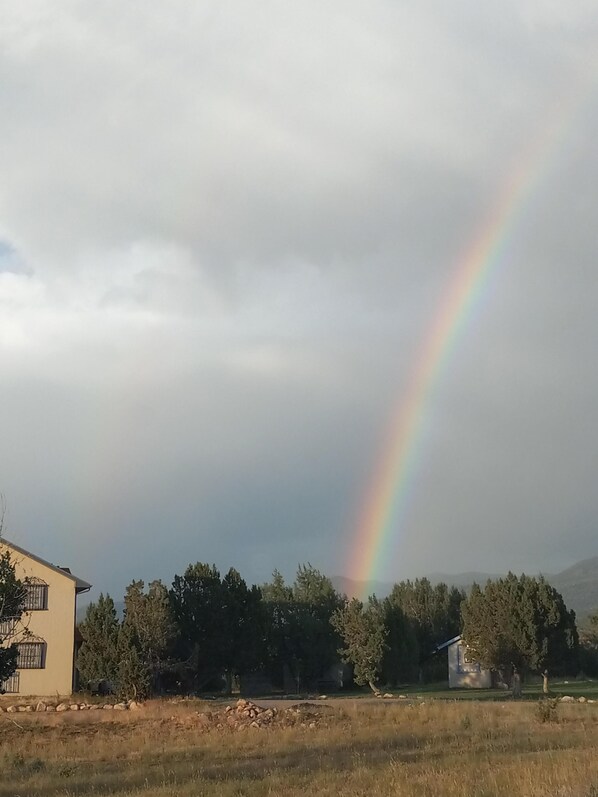 A house with a visible garden and a rainbow in the background.