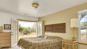 A bedroom with a bed, a dresser, a lamp, and a window with a view of the outdoors.