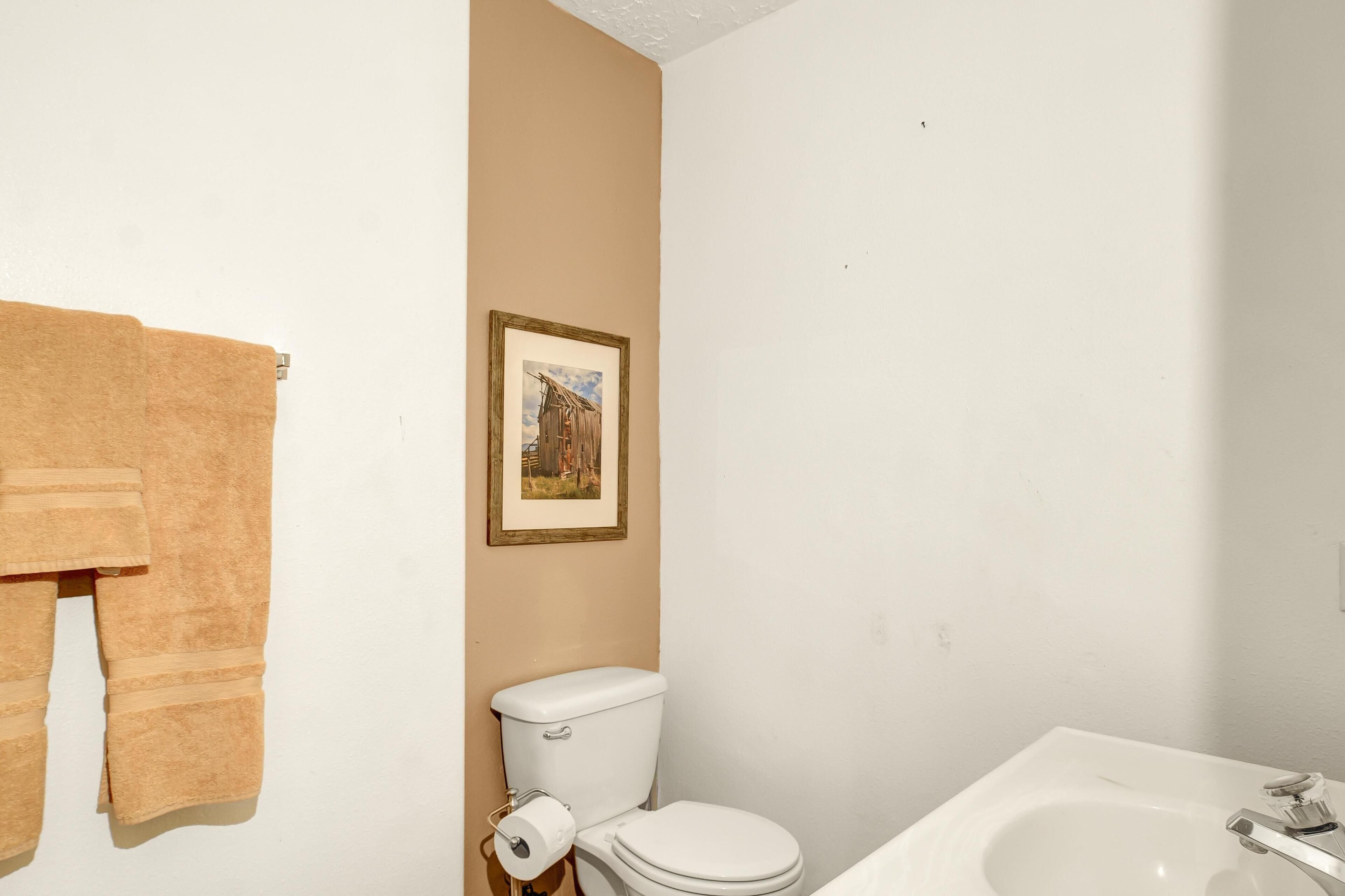 Un baño con inodoro, lavamanos y un cuadro en la pared.