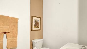 Un baño con inodoro, lavamanos y un cuadro en la pared.