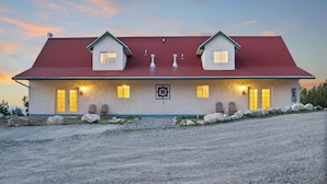 A two-story house with a red roof, multiple windows, and a front porch with chairs. - Ranchette Ponderosa - The La Sal #4 at Wind Walker Homestead (Spring City)