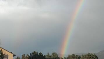 Ein Haus mit sichtbarem Garten und einem Regenbogen im Hintergrund.