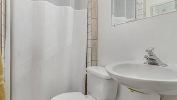 Un baño con inodoro blanco, lavamanos y cortina de ducha.