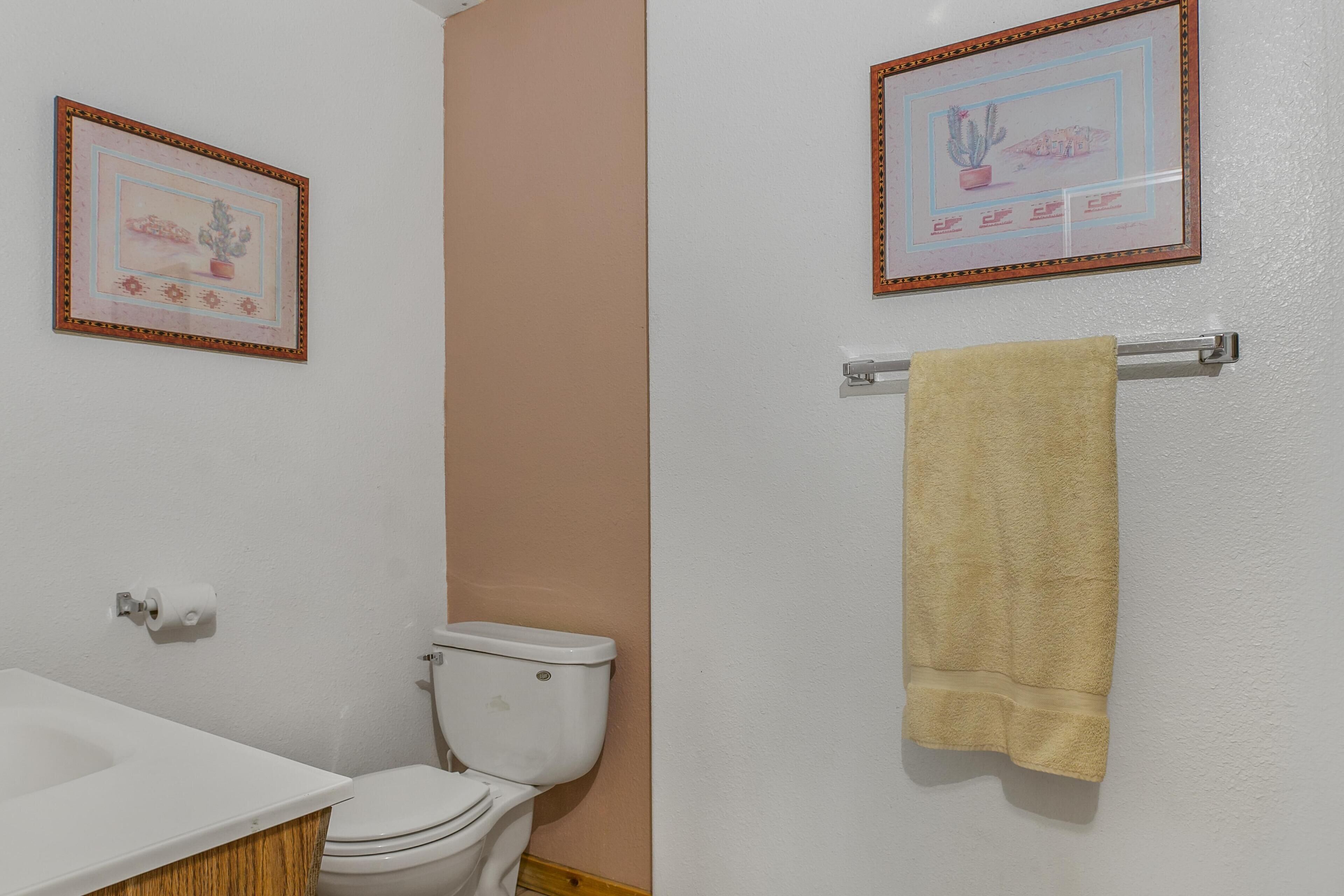 Un baño con inodoro, lavamanos y perchero para toallas.