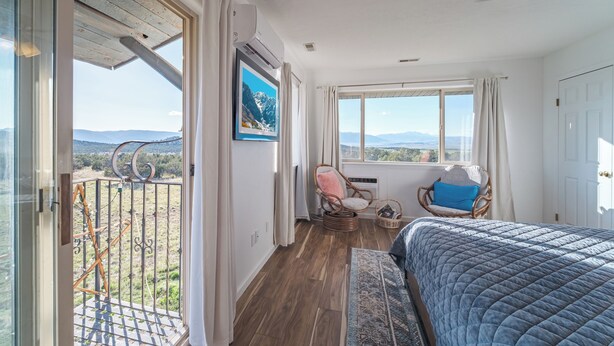 A bedroom with a large bed, a ceiling fan, and a view of the outdoors. - The Harmony Studio at Wind Walker Homestead (Spring City)