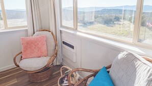 A cozy room with wicker furniture, a view of the outdoors, and a window with curtains. - The Harmony Studio at Wind Walker Homestead (Spring City)
