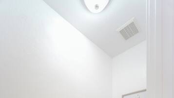 A small, white bathroom with a toilet, a toilet paper holder, and a framed picture on the wall.