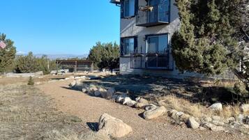 A two-story building with a balcony, surrounded by a dry grassy field and a few trees.