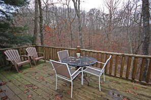 A wooden deck with a round table and chairs, surrounded by a wooden railing.