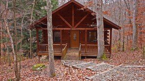 A wooden cabin with a porch, surrounded by trees and fallen leaves. - Grant's Escape - Couples Cabin in Hocking Hills (Logan)