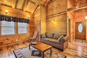 A cozy log cabin interior with a wooden floor, a sofa, a chair, and a coffee table.