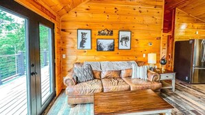 A wooden cabin interior with a leather sofa, a wooden coffee table, and framed pictures on the wall. - Summer Deals/Amazing Views/Dollywood/Pet Friendly (Sevierville)